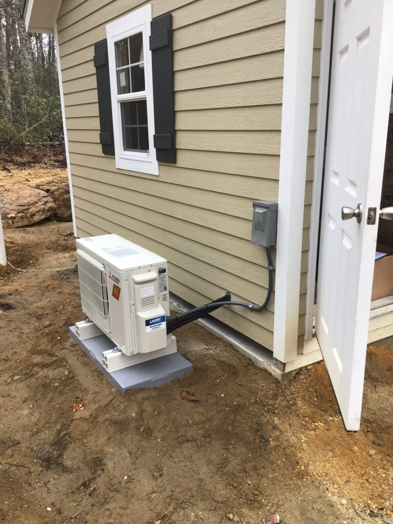 Outdoor condenser unit for a ductless mini-split system installed by Laury Heating in Mays Landing, NJ, next to a home’s siding.