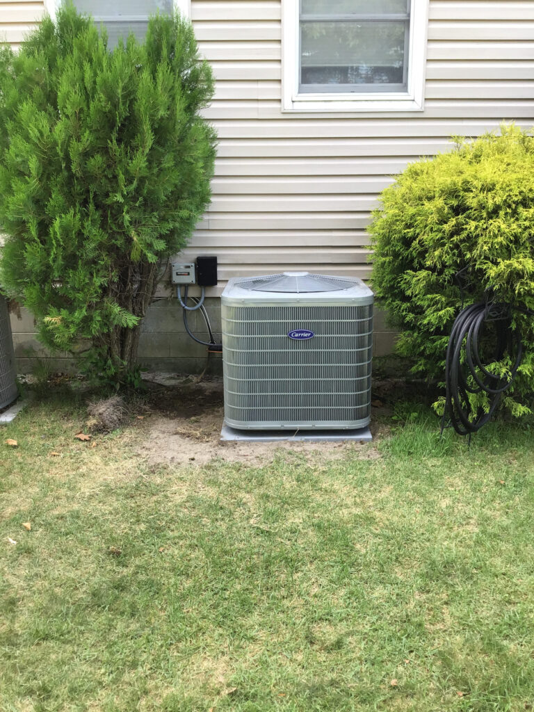 Outdoor air conditioning unit installed beside a residential home with landscaping
