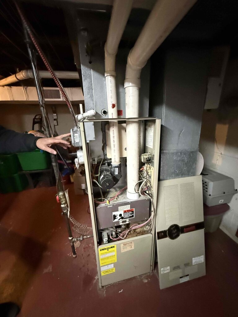 Technician inspecting a residential furnace during an emergency heating repair in a South Jersey home.