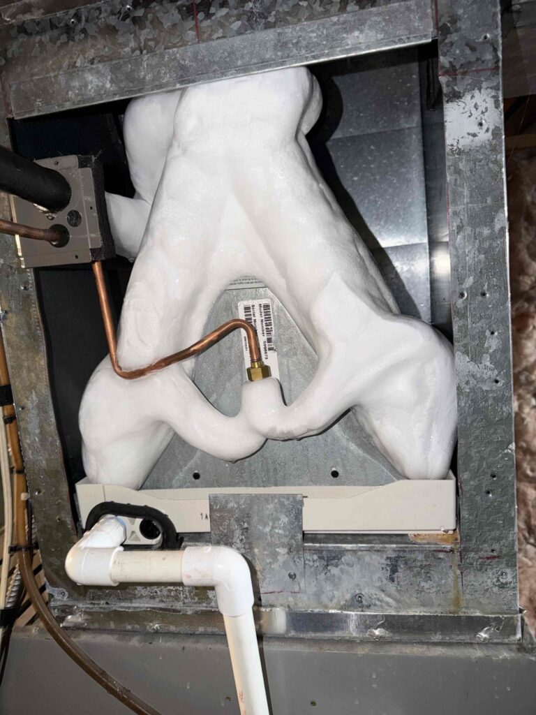 Frozen air conditioning coil covered in ice inside an HVAC system needing AC repair