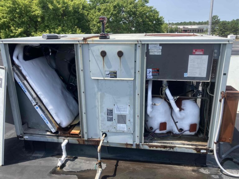 Commercial rooftop air conditioning unit with frozen evaporator coil and visible ice buildup