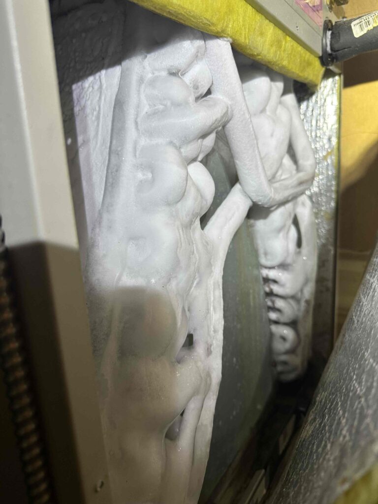Residential AC coil frozen with ice buildup inside an air conditioning system