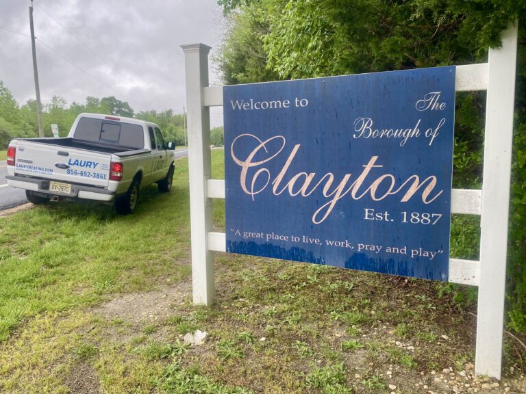 Laury Heating service repair truck parked next to "Welcome To Clayton" sign on road