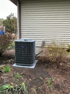 New Carrier outdoor air conditioner installed on an equipment pad beside the home