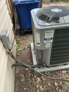Side view of the Carrier air conditioner showing refrigerant lines and electrical connections