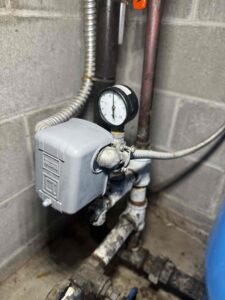 Alt Text:
Well pump pressure switch and pressure gauge beside a blue pressure tank.