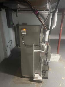 Rear view of the furnace and coil installation, showing gas piping, condensate drains, and a condensate pump.
