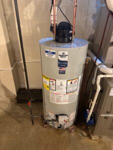 Bradford White gas water heater with a power-vent blower, copper water lines, and PVC exhaust vent.