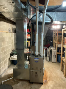 Carrier gas furnace in the basement with PVC vent pipes and an indoor cooling coil above it