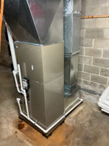 Rear view of the furnace and cooling coil showing sheet metal duct connections and condensate piping