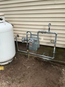 Pressure gauge attached to exterior gas piping beside the natural gas meter