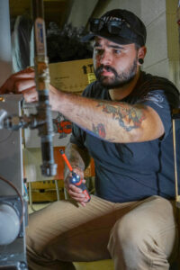 Laury Heating technician working inside a Carrier furnace in a Vineland home