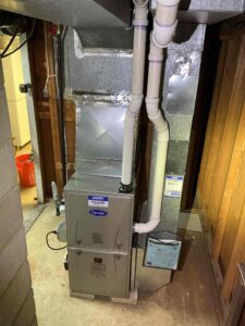 Front view of a new Carrier gas furnace with white vent pipes and overhead ductwork on Strawberry Ave in Vineland.
