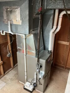 Side view of a Carrier gas furnace with ductwork, vent pipes and a condensate pump in a Vineland basement.